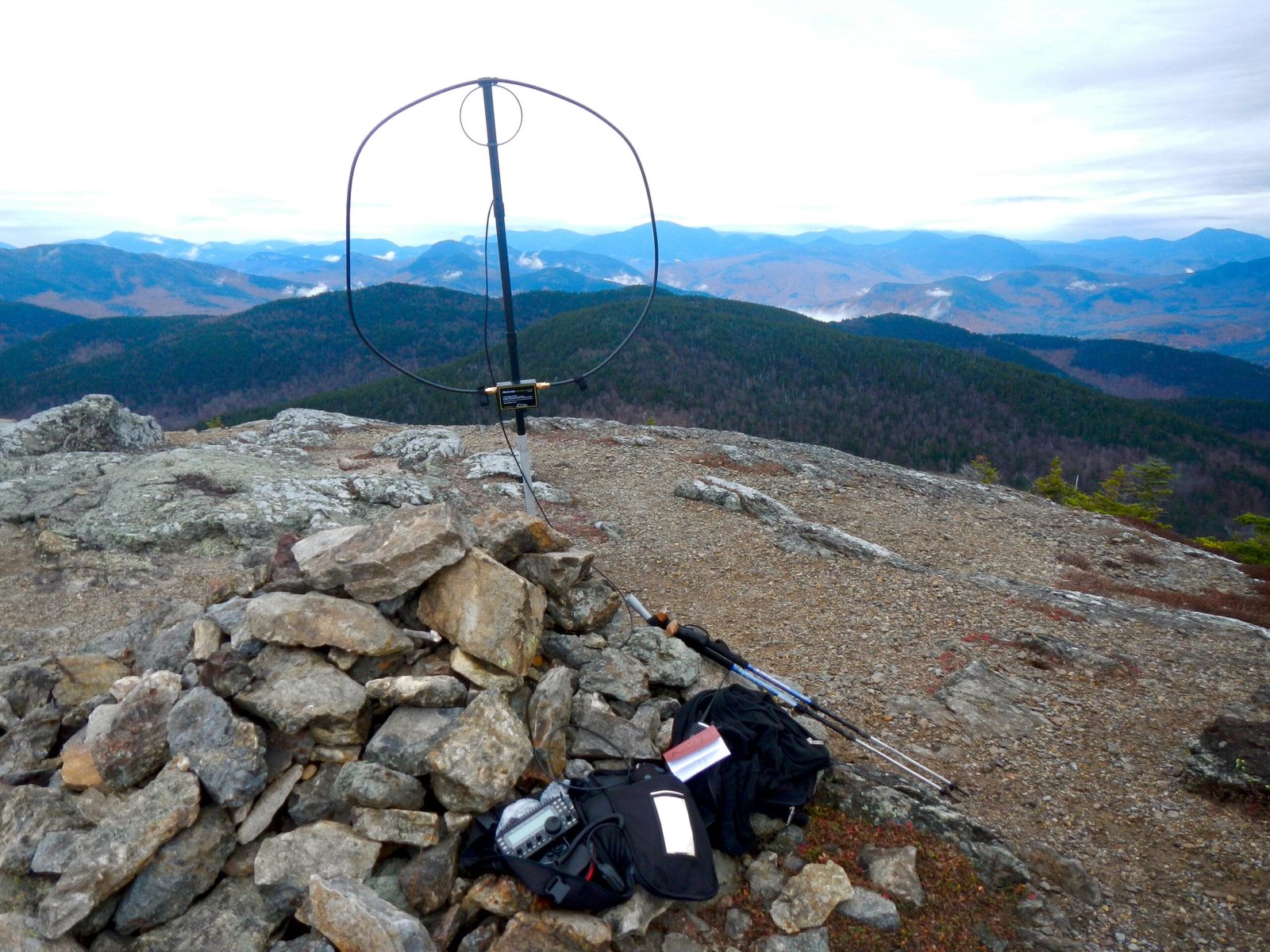 Portable amateur radio station and loop antenna on a rocky summit overlooking mountain ridges
